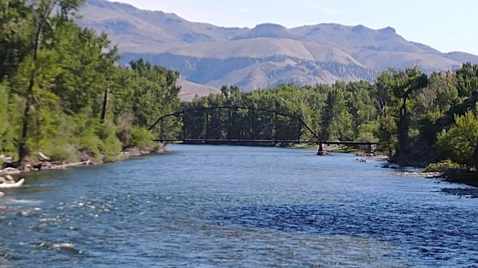 The steel bridge Ralph Hutchison reassembled across the Salmon River, spanning the water with high desert hills behind it.